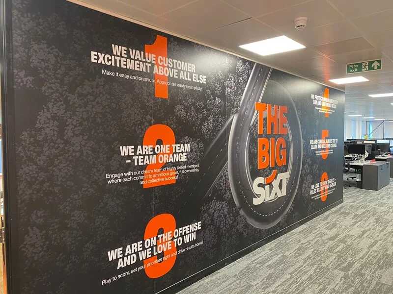 An image of the SIXT interior wall graphics showing text and a winding road.